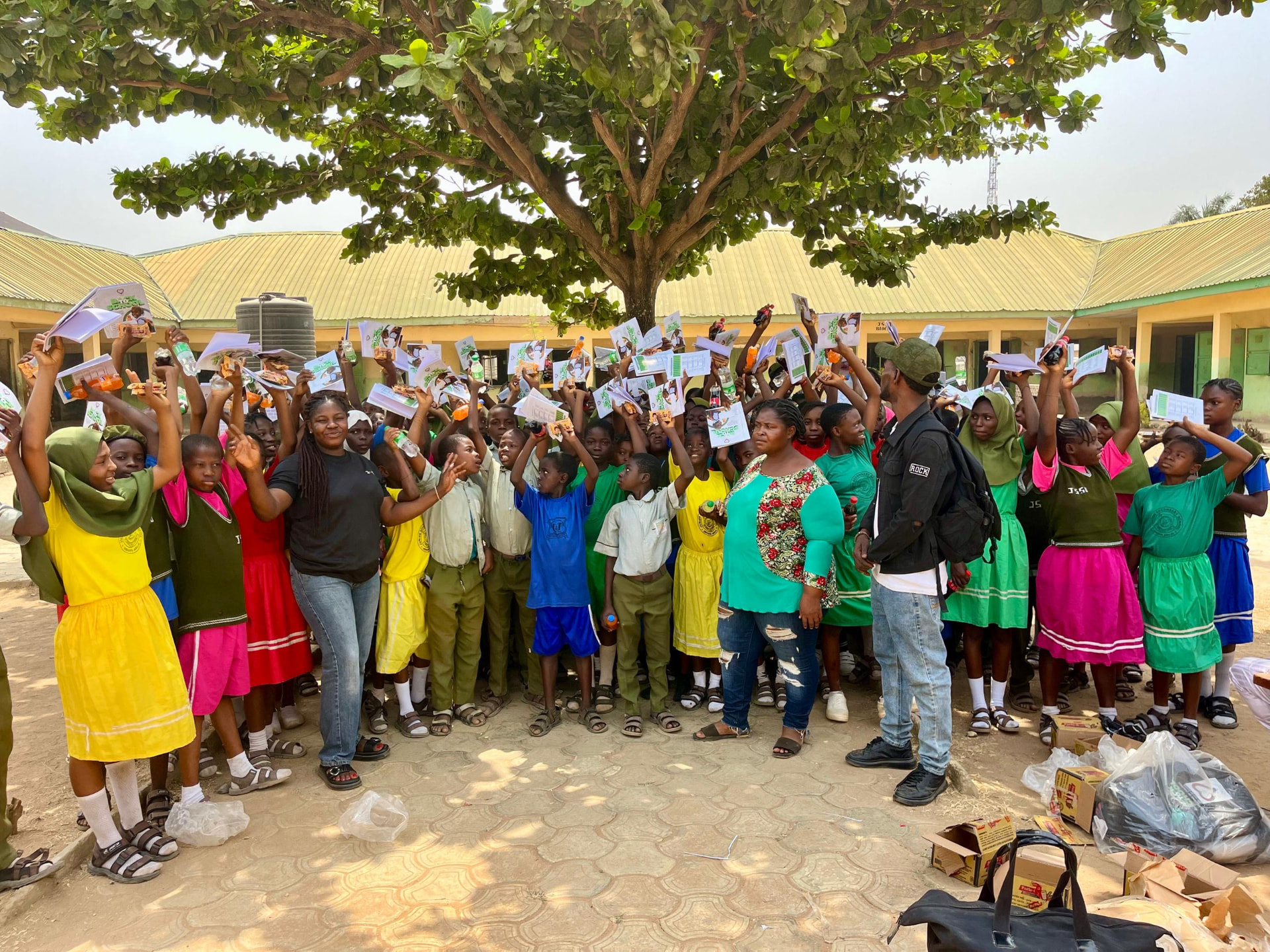 Children receiving new exercise books and school bags from a volunteer
