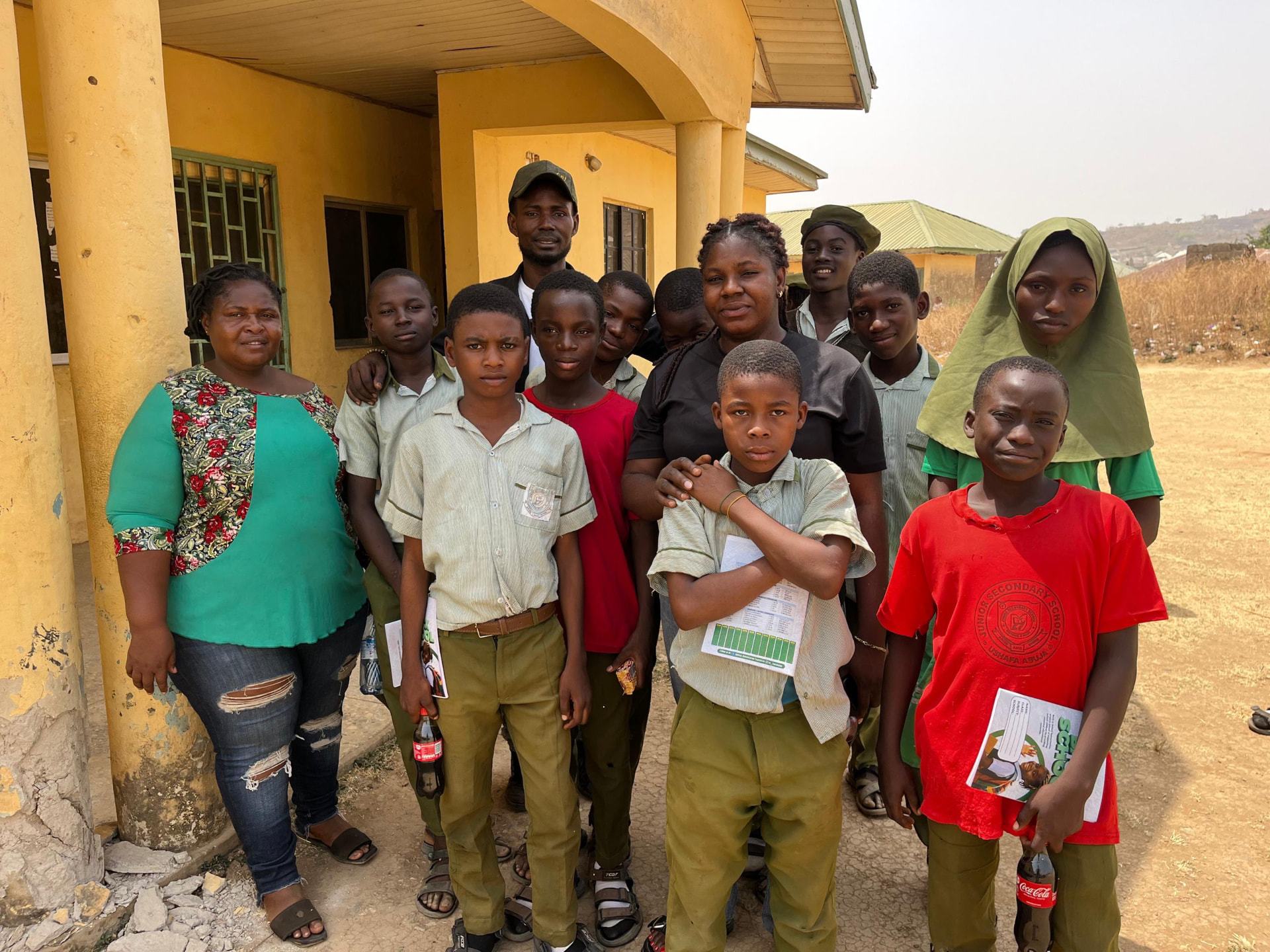 Foundation volunteers with scholarship students holding their school books and progress reports outside their school