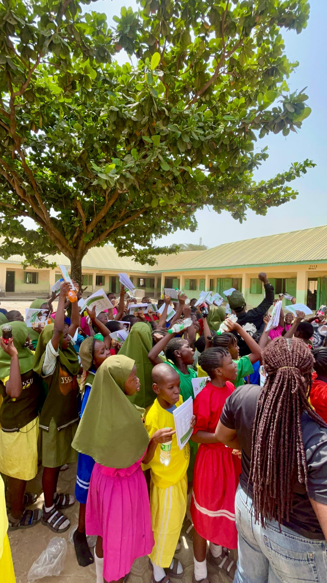 Students celebrating outdoors, raising their notebooks and school materials in the air