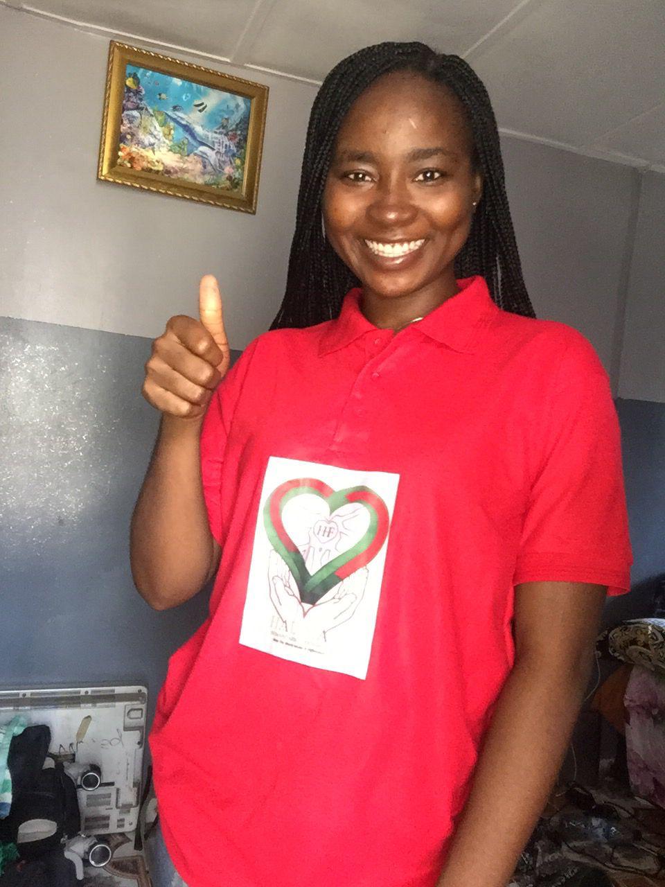 Portrait of Juliet Anthony Ojonimi, Secretary of Halimat Humanitarian Foundation, smiling and wearing the foundation's red branded polo shirt