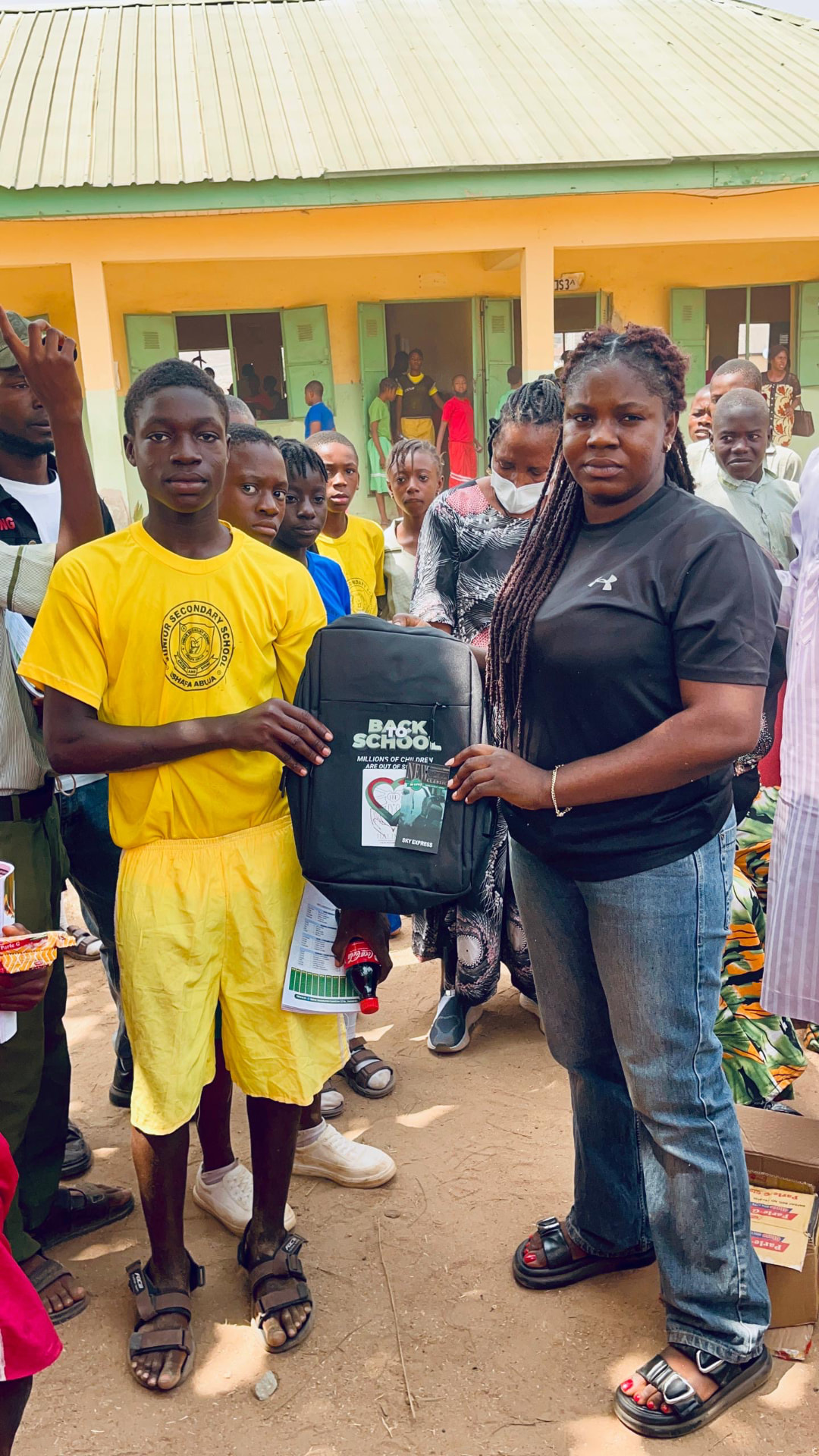 Foundation member handing a new backpack to a student during the Back to School distribution in Bwari, Abuja