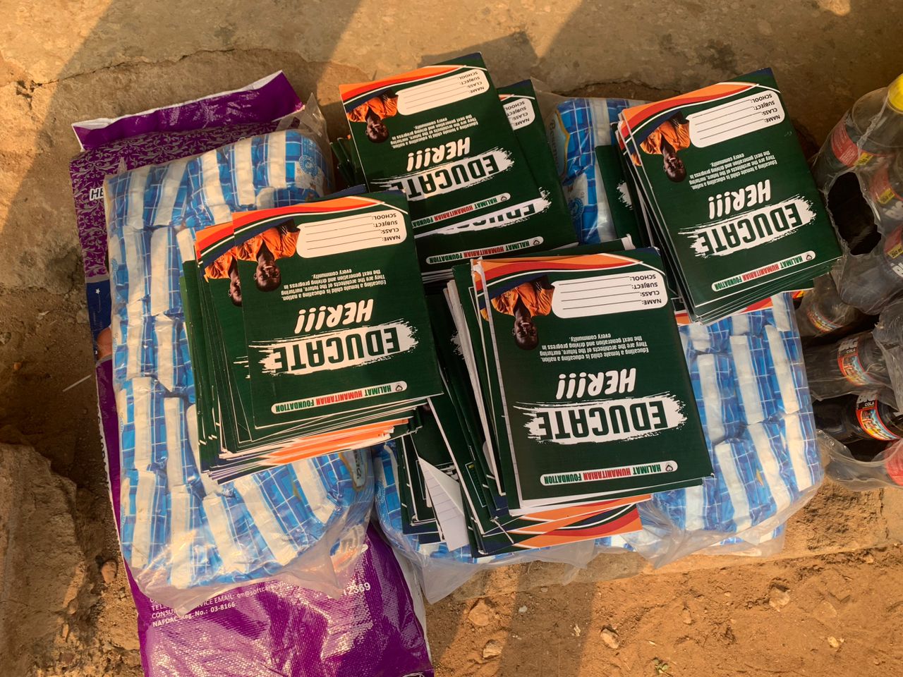 Close-up of stacks of green EDUCATE HER branded notebooks distributed to pupils during the Walk for Humanity education outreach